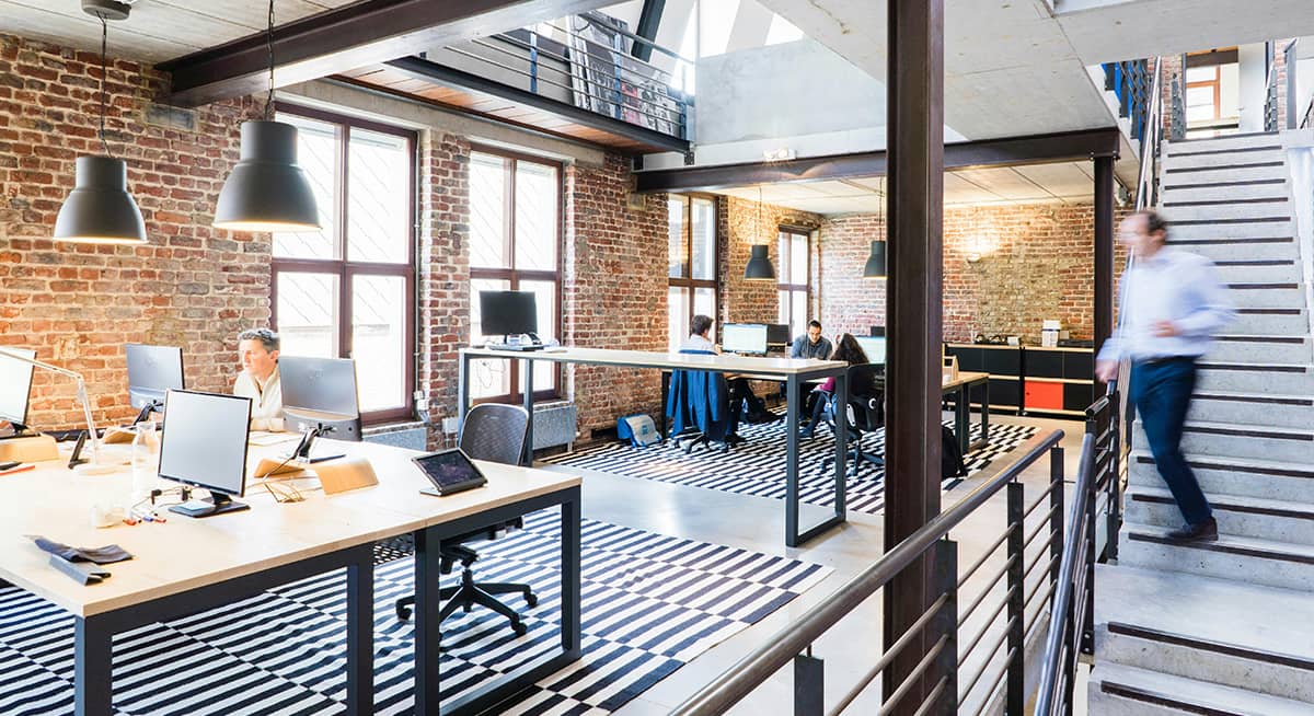 Office space with people at desks and man walking down stairs